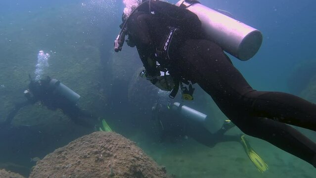 scuba divers exploring in low visibility water - side profile