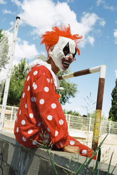 scary clown sitting outdoors, 35mm