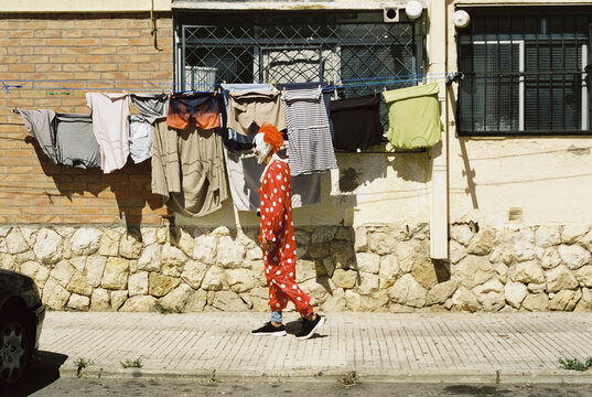 man wearing a clown mask and costume on the street, 35mm