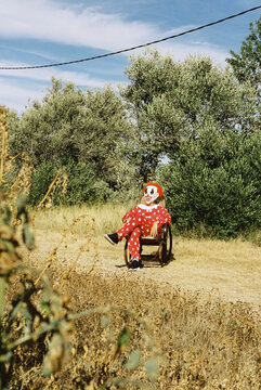 scary clown sitting on a rocking chair outdoors, 35mm