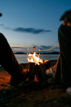 A man and a woman roast marshmallows on a bonfire
