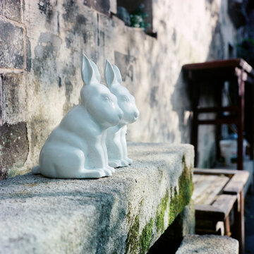 There are two white ceramic rabbits on the windowsill
