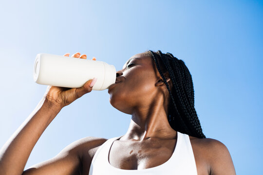 a woman drinks sports water after a morning run