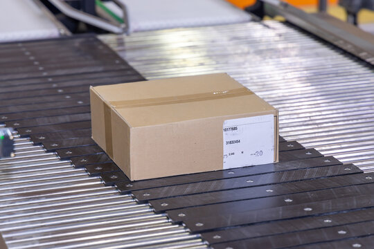 Logistics Efficiency - Cardboard Box on Conveyor Belt in Distribution Warehouse. Parcel Moving Through Automated Shipping System. Streamlined Order Fulfillment - Box in Transit on Warehouse Conveyor