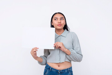 A young pensive Asian woman looking the left, holding a white blank board with space for text....