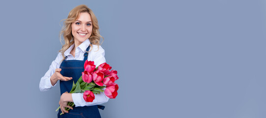 cheerful girl in apron with spring tulip flowers on grey background. Woman isolated face portrait, banner with mock up copy space.