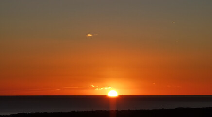 Il Sole accecante che all’alba sorge dal mare visto da sopra le colline 