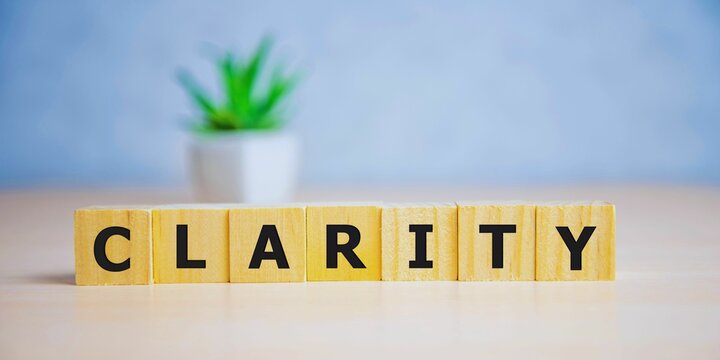 word CLARITY with wood building blocks, light green background. front view.