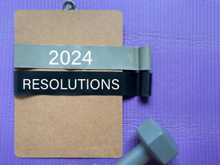 2024 Resolutions text with exercise equipment background. Fitness Resolutions Concept.