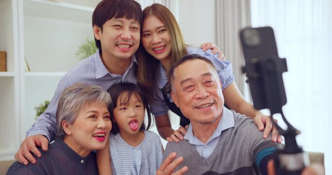 Multigenerational family sharing a light-hearted moment while taking a group selfie with a smartphone at home.