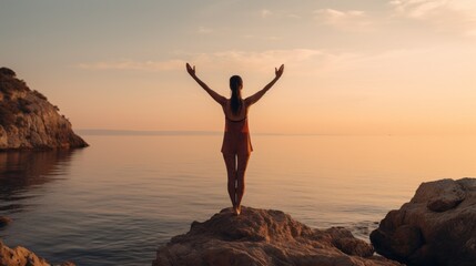 Rear view of a woman practicing Yoga standing with her arms outstretched in the open air near the sea at Sunset. Sports, Travel, Summer, Training, Meditation, Healthy Lifestyle concepts.