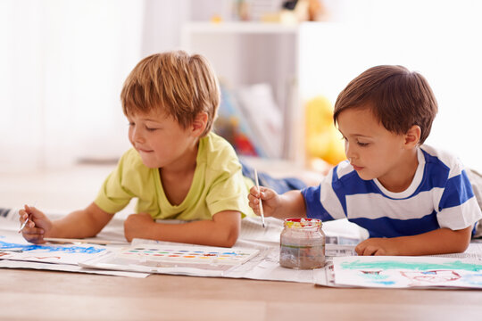 Young children, painting and creative with paint brush on floor or playing room, hobby and drawing together at home. Brothers, motor skills and growth for childhood development with smile for artwork
