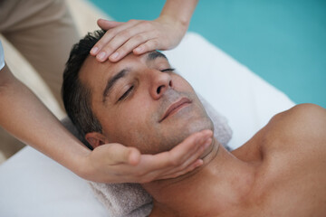 Hotel, spa and man relax for facial massage on table in resort, calm and care for body in vacation....