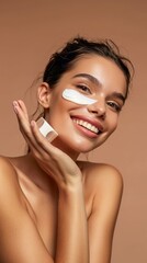 Close up of young woman applying sun cream and touch own face. Skin Protection and dermatology. Girl is smiling. Light background.