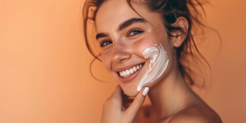 Close up of young woman applying sun cream and touch own face. Skin Protection and dermatology. Girl is smiling. Light background.