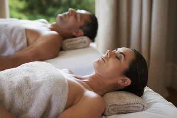 Fotobehang Massagesalon Luxury, massage and couple relax in spa for care of body with rest on bed of retreat for honeymoon. Hotel, man and woman together in resort for health, wellness and holiday for skincare in break