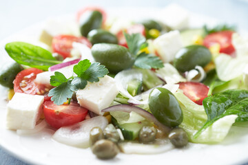 Healthy Salad with Feta Cheese, Green Olives, Baby Spinach, Cucumber, Cherry Tomatoes and Capers. Bright background. Close up.	
