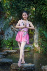 Beautiful girl ballerina dancing. Ballerina Project Show in the nature. A girl poses as a ballet performer in the green natural park. She was posting relax, and happiness.