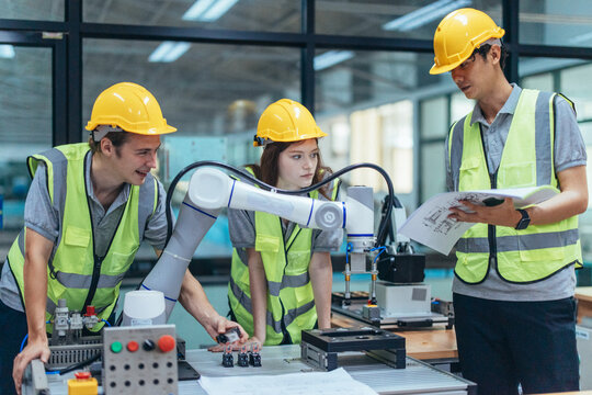 Trainees programing robotic arm in practical lesson at robotics academy, focusing on hands-on skills