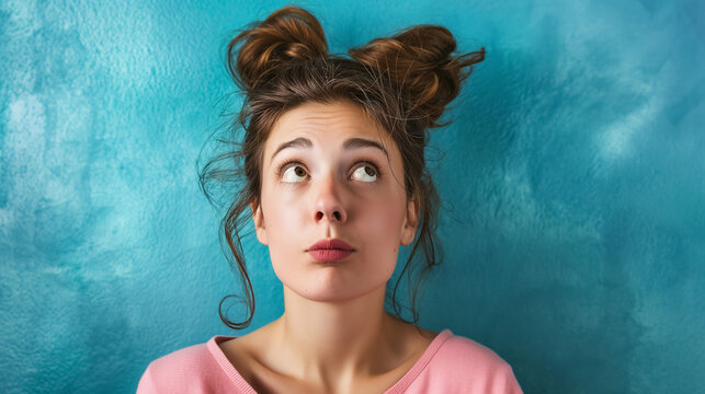 Young woman thinking against blue wall.