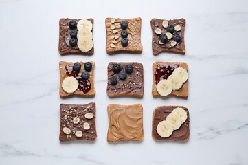 Different tasty toasts with nut butter and products on white marble table, flat lay