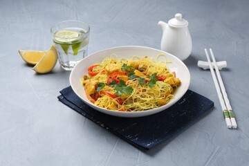 Stir-fry. Delicious cooked noodles with chicken and vegetables in bowl served on gray textured table