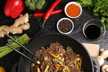 Stir-fry. Tasty noodles with meat and vegetables in wok served on dark textured table, flat lay
