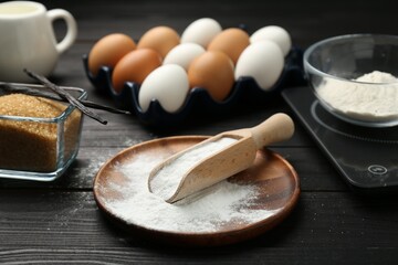 Baking powder and other products on black wooden table, closeup