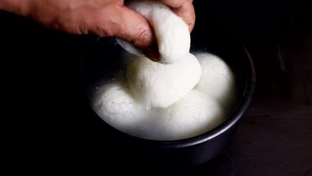 squeezing a spongy Rasgulla one of the popular Indian sweet.