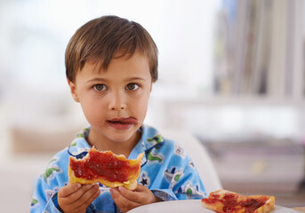 Portait, food, and breakfast for young boy eating, bread and pyjamas in home for nutrition. Children, childhood and development with toast for health, jam and snack or wellness for kid male person