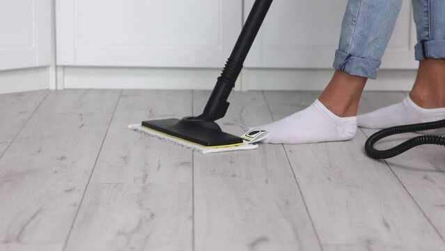 The janitor removed the soft pad from the mop mop after cleaning. Close-up of female feet with white socks doing wet cleaning of floor indoors