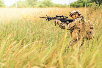 Fototapeta premium The captain of the military unit was in the grass. Prepare the M16 rifle. Send out your rifle and shoot enemies at range in the jungle battlefield. Wear camouflage clothing, a backpack, and sunglasses