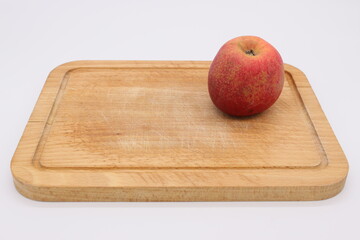 Image of a red apple on a cutting board on a light background.