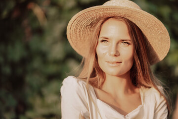 Woman with straw hat stands in front of vineyard. She is wearing a light dress and posing for a photo. Travel concept to different countries