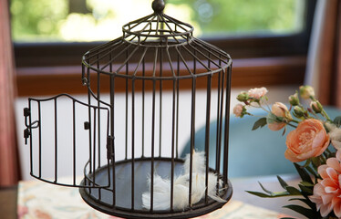 Floral decoration and bird cage of escaped birds in a room with a window