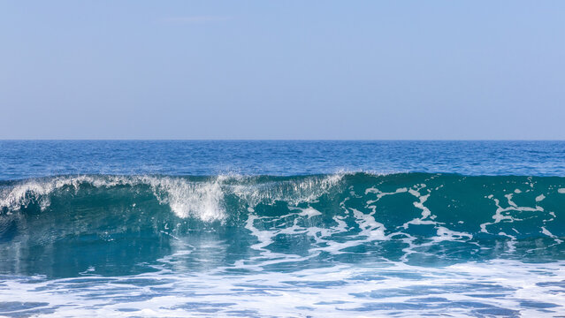 Front view of nice wave rolling in and breaking with empty blue sky horizon in Gran Canaria, Spain