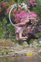 Beautiful Asian girl performing show aerial hoop or aerial ring in various positions and spinning stunts on the blue sky.