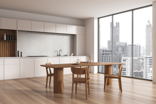 Beige home kitchen interior with eating table and chairs, panoramic window