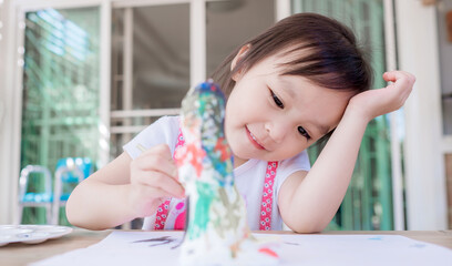 Cute little girl painting color on DIY plaster painting toy at home. Soft focus. Copy space.