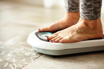 Fototapeta premium photo of woman weighing herself on scale