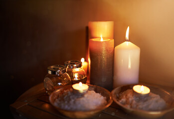 Spa, candle and oil with salt for meditation in room for peace or luxury with aromatherapy to relax. Aromatic or cosmetic liquid, table and candlelight for mindfulness or wellness and self care.