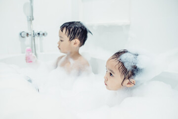 Cute little boy and girl taking bath playing with foam and soap bubbles. Hygiene for infant and baby. Soft focus. Copy space.	