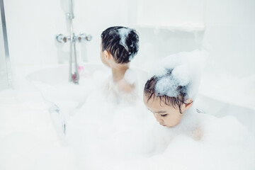 Cute little boy and girl taking bath playing with foam and soap bubbles. Hygiene for infant and baby. Soft focus. Copy space.	