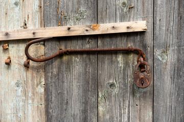 gray wooden wall with padlock and slats held with nails
