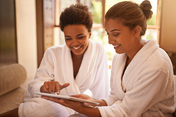 Beauty, tablet and spa with woman friends in robes for luxury pampering or treatment together. Smile, tech and social media with happy young people at resort or salon for wellness or weekend getaway