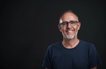 Obraz premium Casual Mature Man with Glasses Smiling on Dark Background - Relaxed Portrait