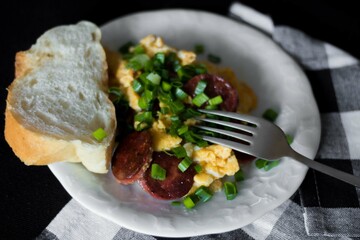 Homemade scrambled eggs sprinkled with green chives with fresh bread