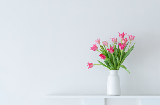 pink tulips in white vase on white background