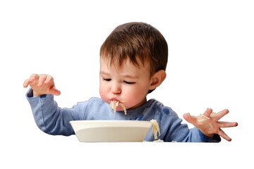 A funny child is eating a grated apple with mouth full while sitting on a kitchen chair, isolated on white background. Hungry baby boy shoves food in his mouth, humor. Kid aged one year four months