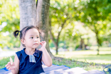 Cute little asian boy eating chips or potato wafers at park. Copy space.